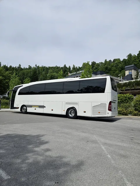Side view of a white touring coach in a parking area