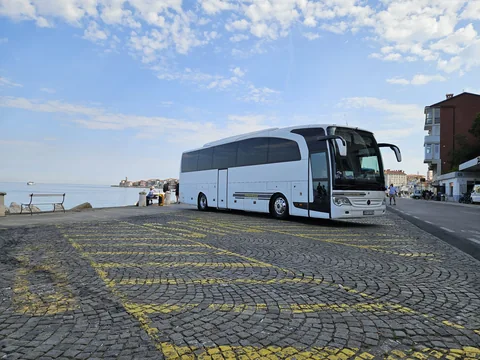 White coach parked beside the sea under a blue sky