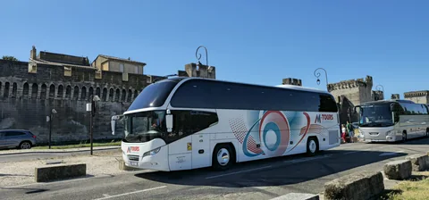 Side view of a touring coach with a historic building behind it
