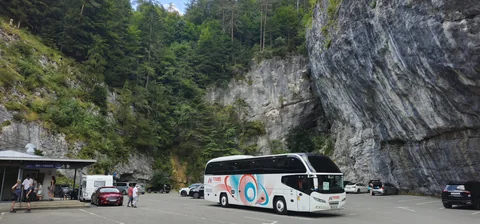 Coach parked below a tall rock face